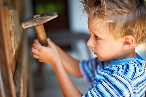 Little boy trying to hammer a nail